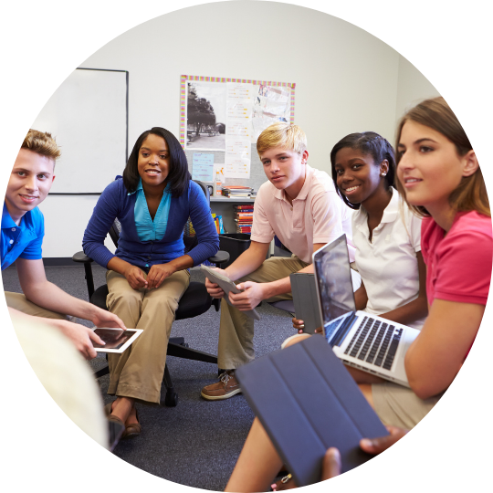  5 teens seated in a circle holding electronic devices